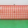 Orange safety barrier netting creating a flexible protective guardrail for warehouse safety zones.