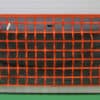 Orange safety barrier netting installed as a flexible guardrail for warehouse fall protection.