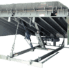 Mechanical dock leveler underside showing steel deck supports, lift arms, and operating mechanism.