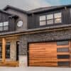 A CHI Double Plank Garage Door with windows down the right side in cedar