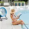 Blue fan next to woman reading by the pool
