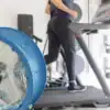 Blue fan on floor in a home gym pointing at someone running on a treadmill